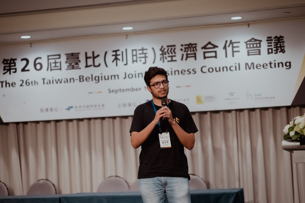 Man presenting with microphone at the 26th Taiwan-Belgium Joint Business Council Meeting on stage.