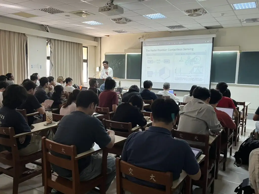 Speaker presenting a lecture on contactless radar sensing to university students sitting in a classroom.