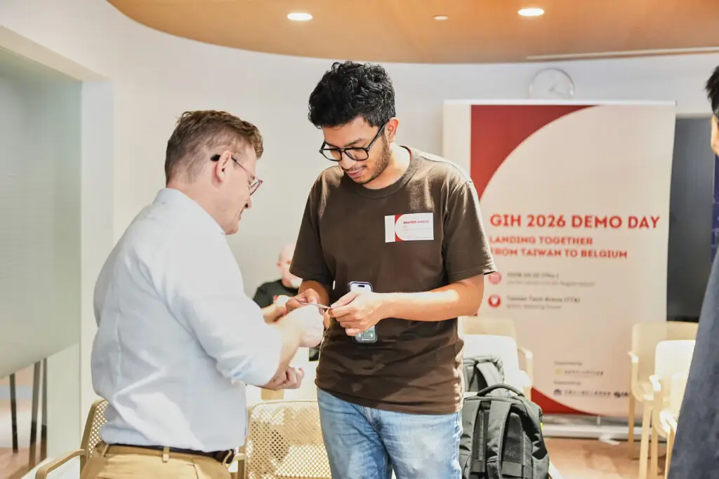 Two professionals exchanging business cards at a GIH Demo Day networking event.