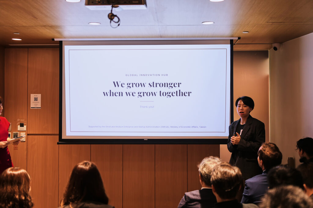 Speaker giving a Global Innovation Hub presentation with a slide stating, We grow stronger when we grow together.