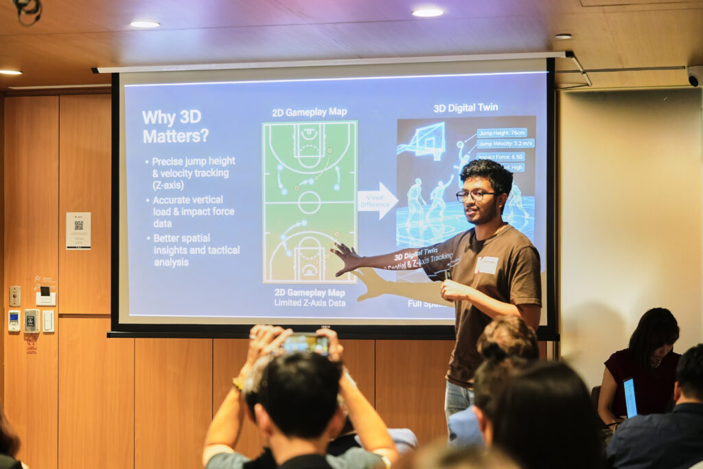Presenter pointing to a presentation slide on 3D digital twins and sports tracking technology.