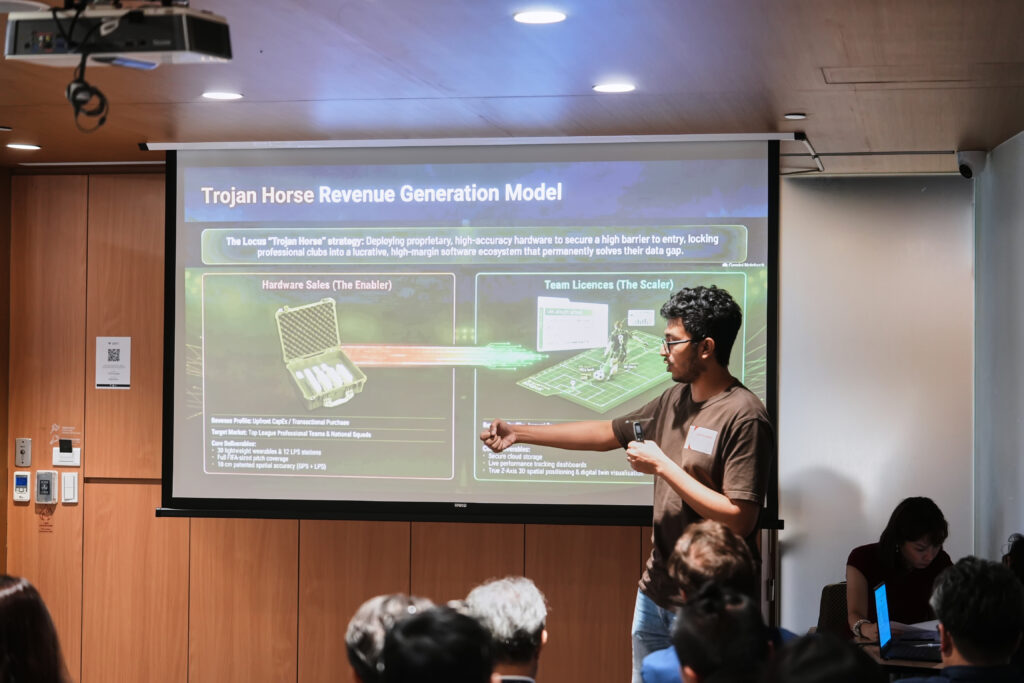 Speaker presenting a Trojan Horse Revenue Generation Model slide on a projector screen to an audience.