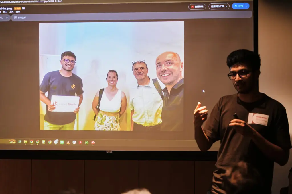 A speaker presenting next to a projected photo of four colleagues holding a Locus Sports sign.
