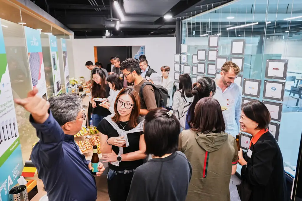 Diverse professionals networking and conversing at a busy tech startup event and exhibition.