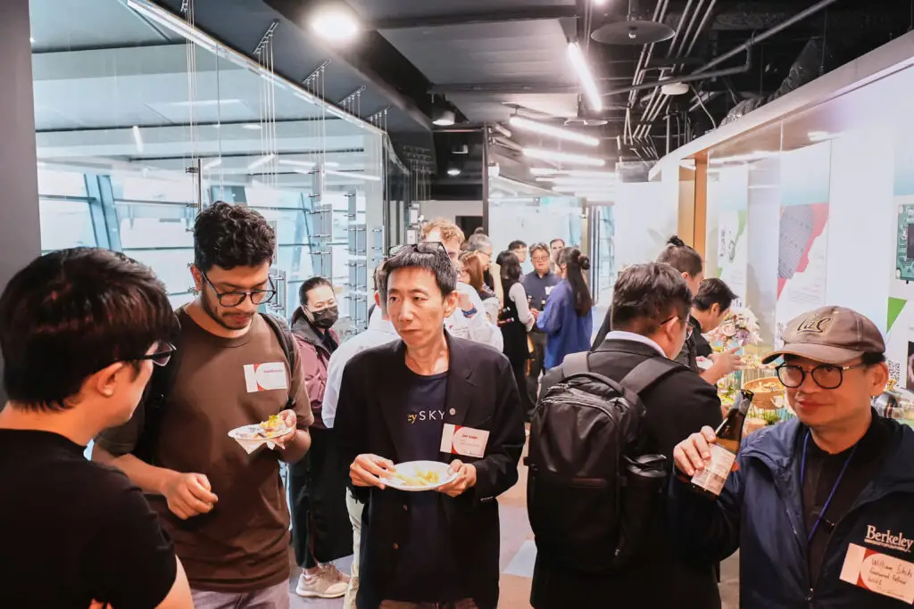 Professionals networking and enjoying refreshments during an indoor tech conference reception.